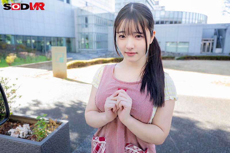 保育士エプロン姿の彩月七緒が屋外で両手を組み微笑む、VR主観に近い近距離アップのサンプル画像