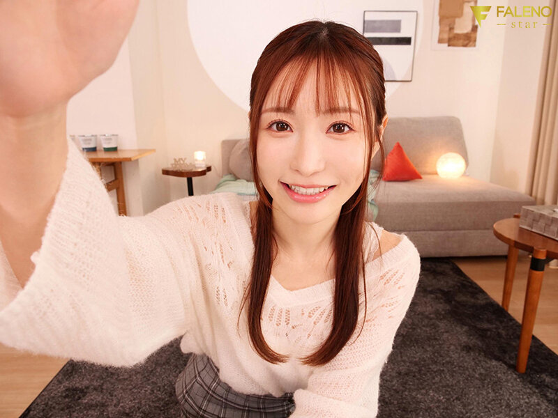 VR主観視点で天使もえが目の前に手を伸ばしてくる近距離の笑顔カット。白ニット姿でソファのある室内シーン