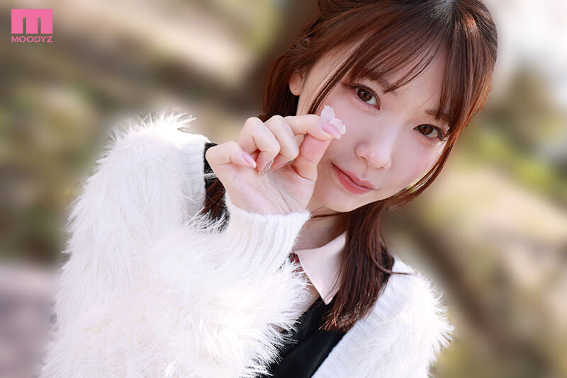 白いファー風カーディガン姿の石川澪が、小さな花びらを指先でつまんで見せる近距離カット