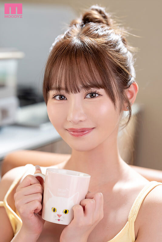 お団子ヘアの女性が黄色いキャミソール姿で、猫柄のマグカップを両手で持って微笑んでいる