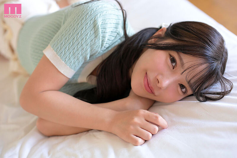 ベッドにうつ伏せで頬杖をつき、間近でこちらに微笑みかける近距離クローズアップのサンプル画像